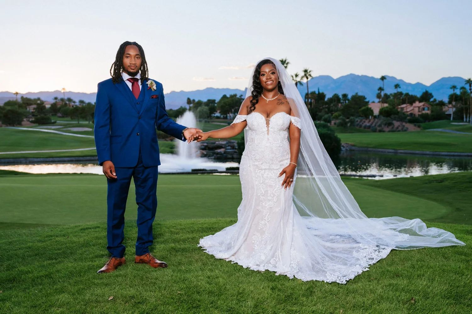 Las Vegas wedding photography — holding hands by a fountain with lake and mountains behind