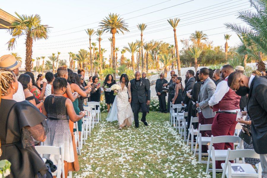 Las Vegas wedding photography — the couple walking the petal-covered aisle under tall palms