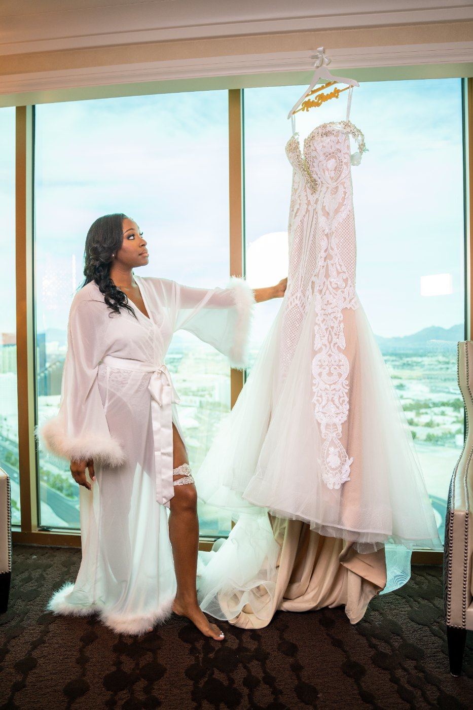 Las Vegas wedding photography — the bride with her gown hanging at the suite window
