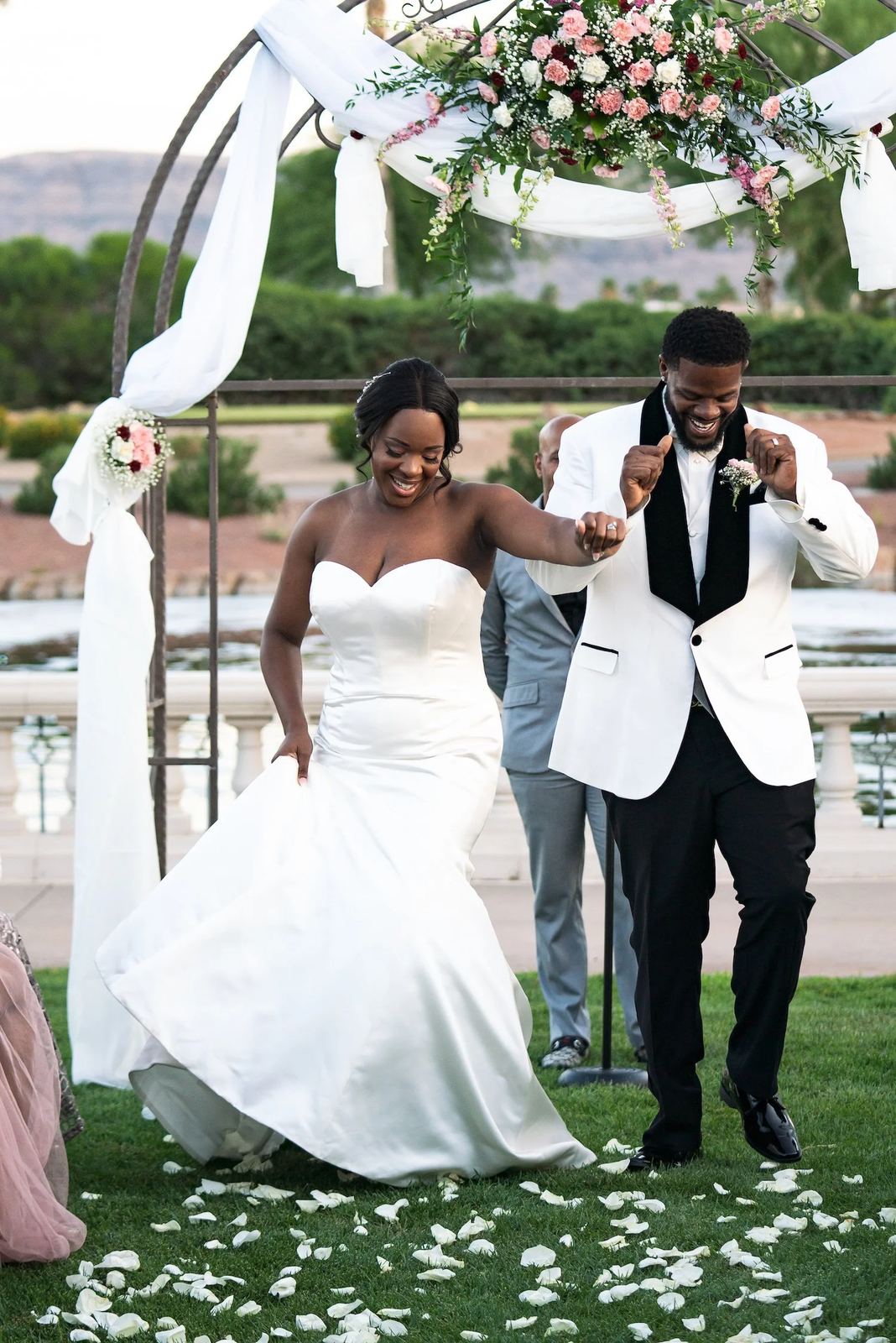 Las Vegas wedding photography — celebrating under a floral arch with petals on the grass