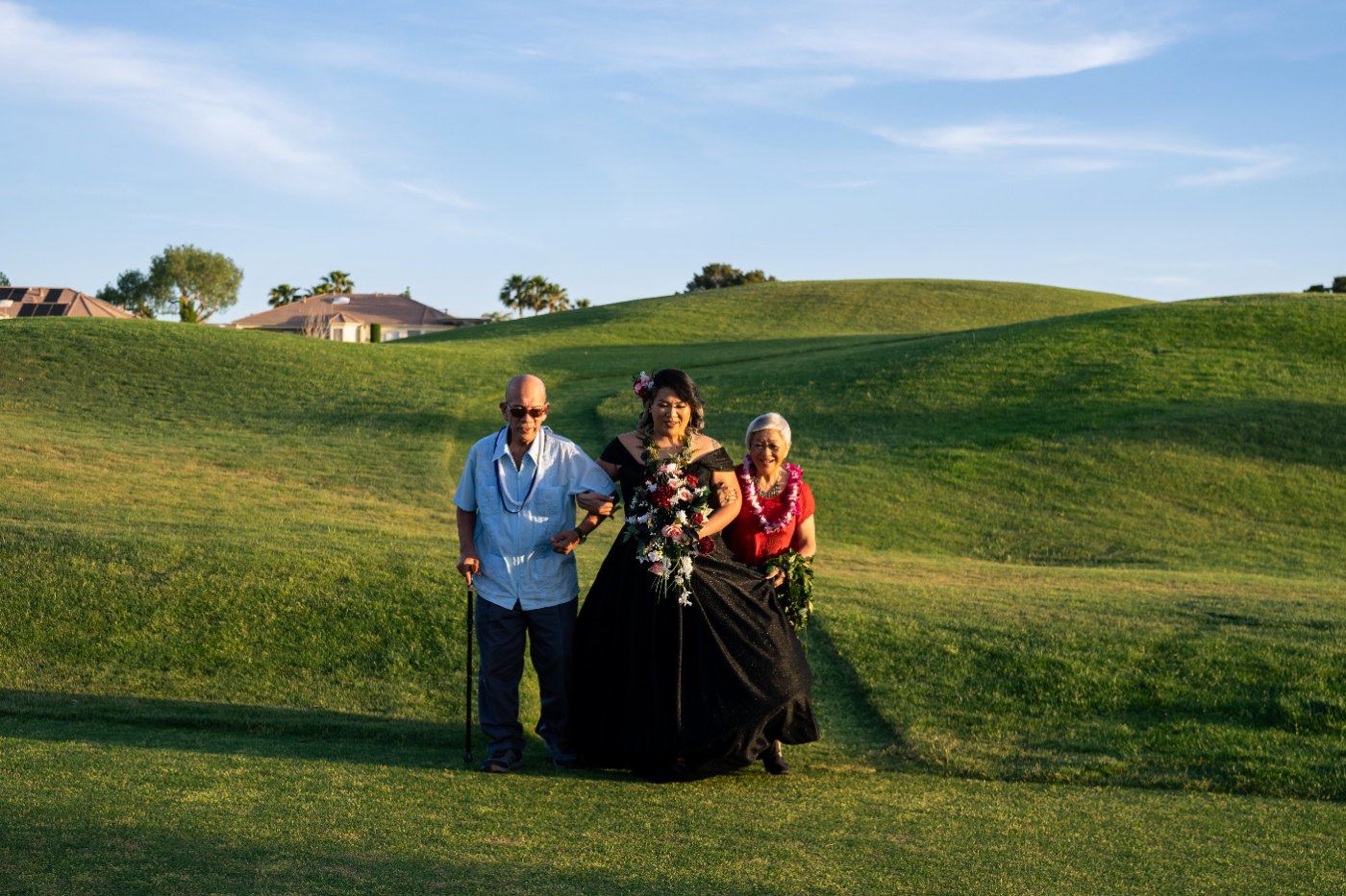 Las Vegas wedding photography — the bride walking the aisle with her parents across the green