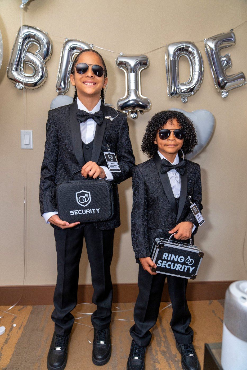 Las Vegas wedding photography — two young ring bearers in tuxedos and sunglasses with “ring security” cases