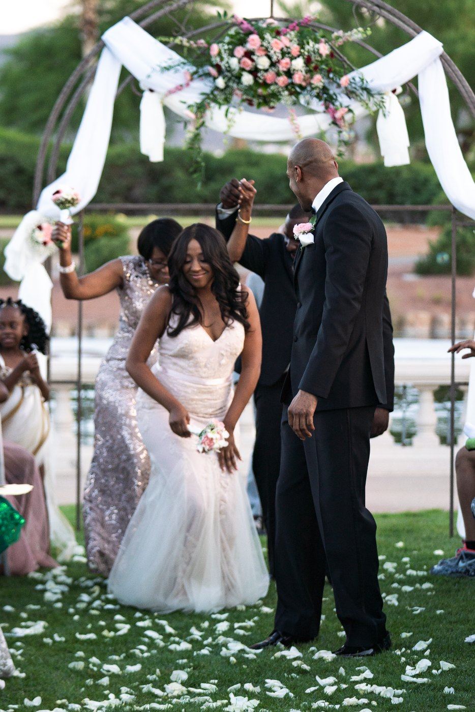 Las Vegas wedding photography — the bride walking in with her father under the floral arch