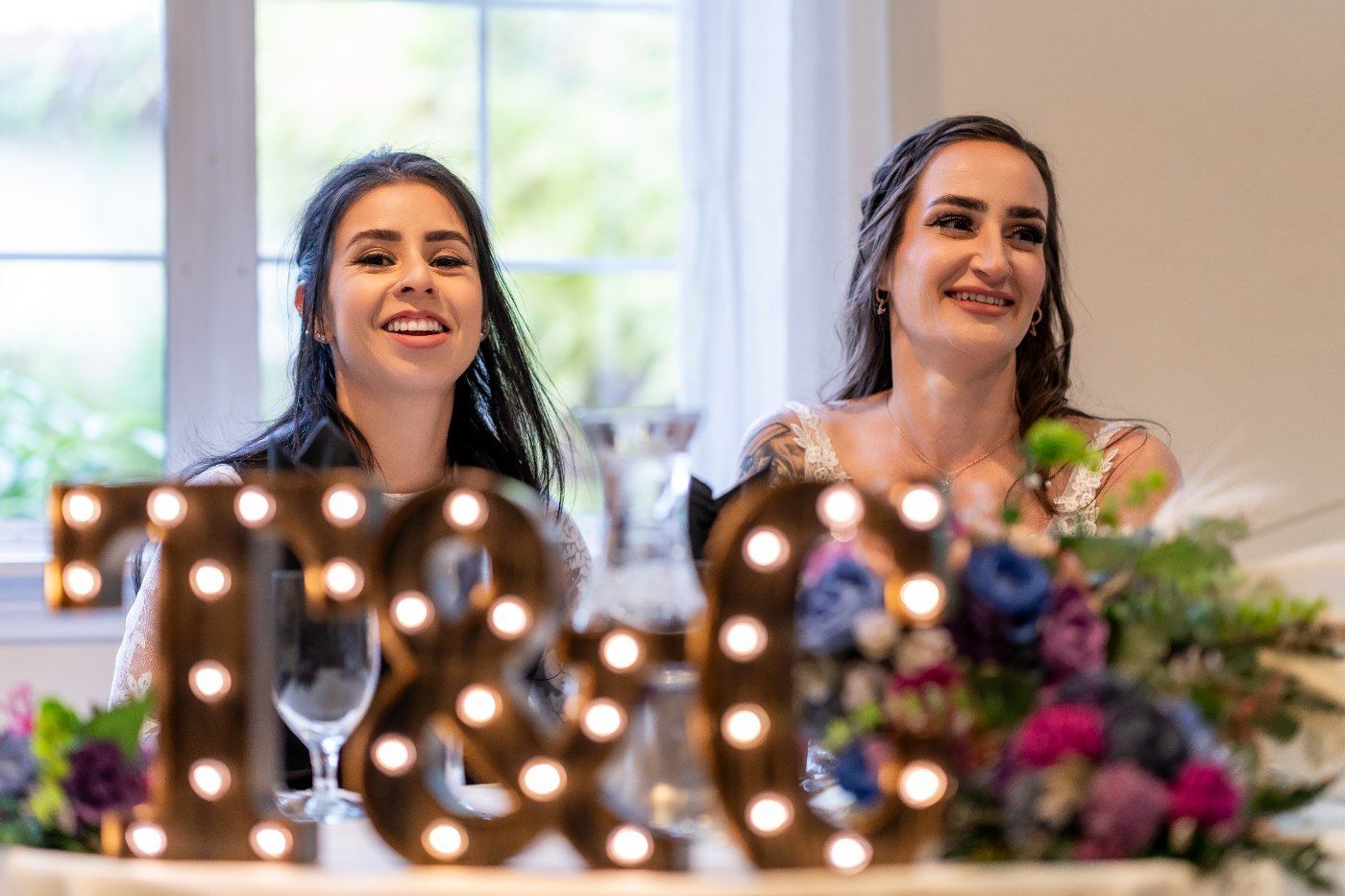 Las Vegas wedding photography — the couple laughing behind lit marquee letters at the reception